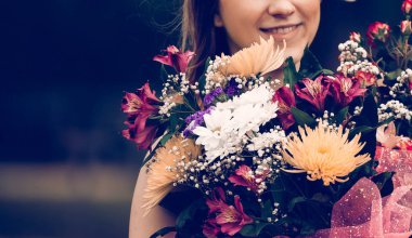 Park 'ın bulanık arka planında bir buket çiçekle güzel bir kadın.