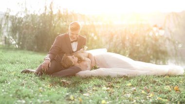 Gelin ve damat şehir parkında çimlerde oturuyor..