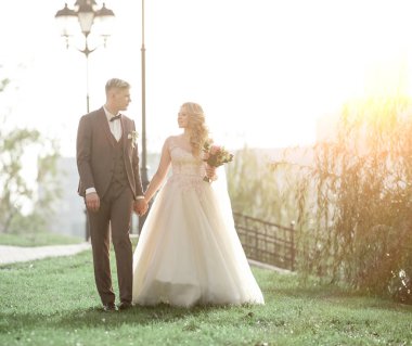 Şehir parkında çimlerin üzerinde yürüyen mutlu yeni evliler..