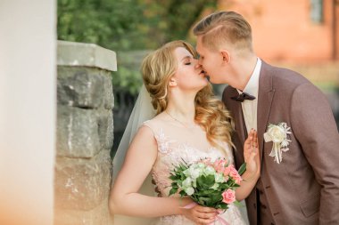 Mutlu yeni evliler sokakta öpüşüyor.