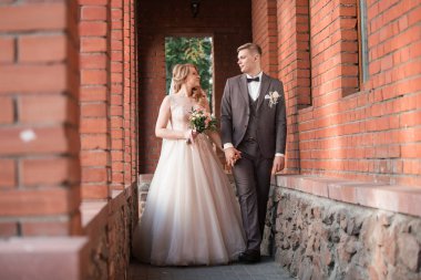 Gelin ve damat eski bir kırmızı tuğla binada duruyor. .