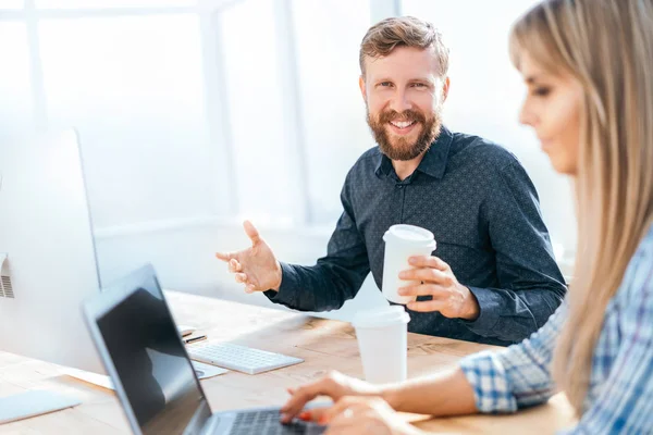 smiling businessman with a glass of coffee sitting at his Desk