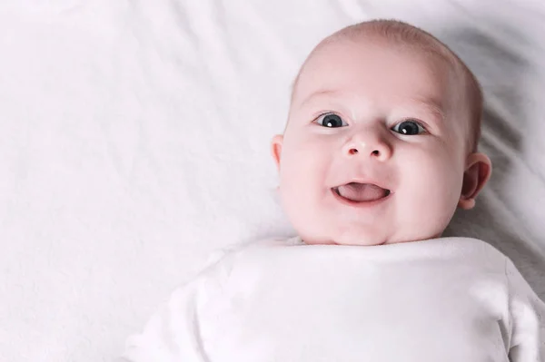 Słodkie uśmiechnięte dziecko leżące na łóżku. — Zdjęcie stockowe