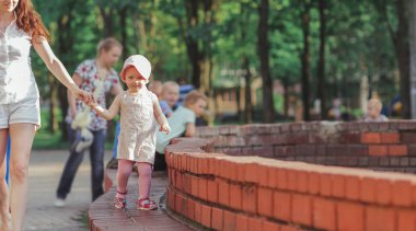 Küçük kızıyla şehir çeşmesinin yanında yürüyüşe çıkmış genç bir anne.