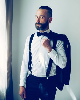 Omzunun üzerinden camdan dışarı bakan zarif bir adam.