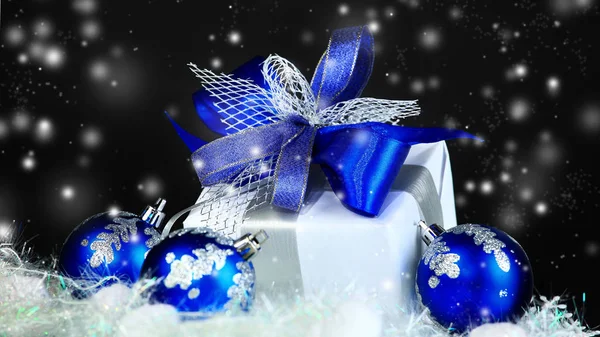 Prezent świąteczny i niebieskie kulki na czarnym tle świątecznym — Zdjęcie stockowe
