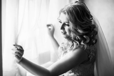 siyah beyaz fotoğraf. Genç bayan gelin pencerenin yanında duruyor.