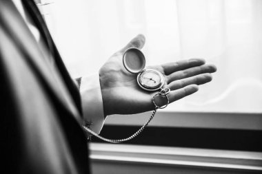 Gürültülü siyah beyaz fotoğraf. Genç işadamı saatine bakıyor..