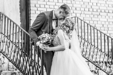 Gelin ve damat tuğladan bir evin verandasında duruyorlar. siyah beyaz fotoğraf