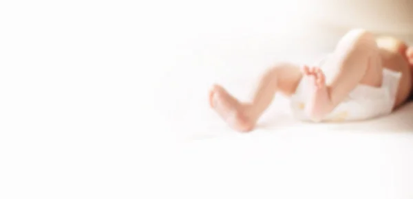 Imagen de las piernas del bebé acostado en la cama. fondo borroso con espacio de copia . —  Fotos de Stock