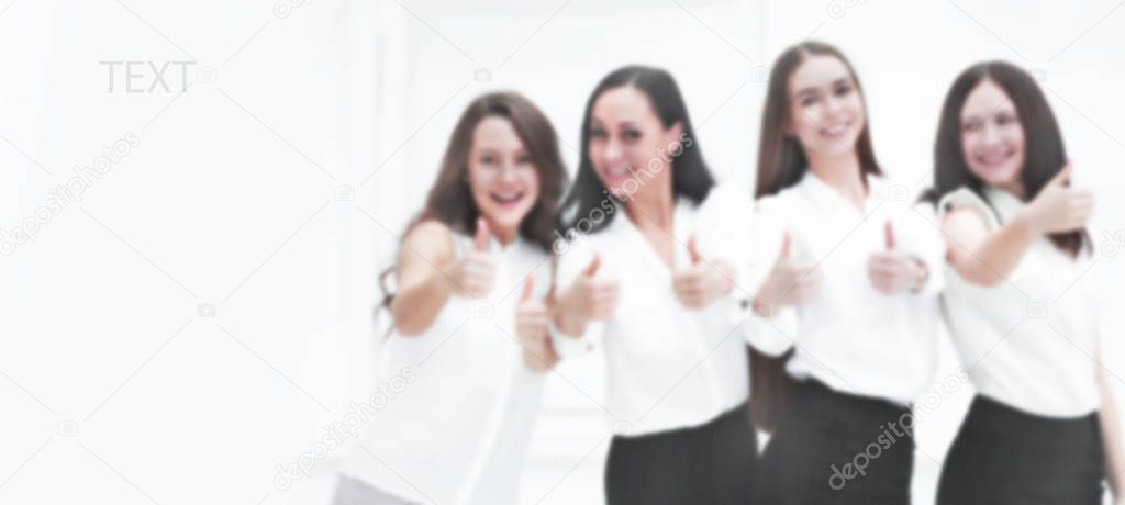 blurred background with copy space. triumphant business team holding thumbs up. teamwork