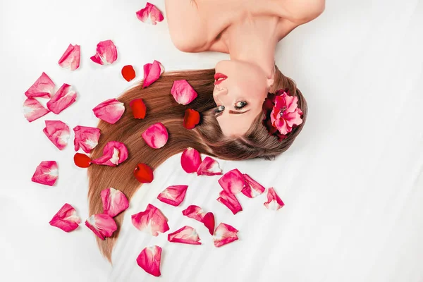 Hermosa chica relax, acostado entre pétalos de rosa —  Fotos de Stock