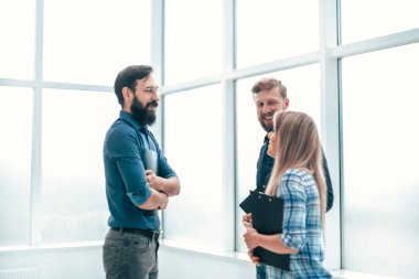 Bir grup iş adamı ofis koridorunda bir şey tartışıyor.