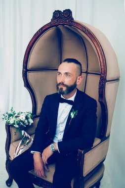 Düşünceli damat bir sandalyede oturan gelinini bekliyor.