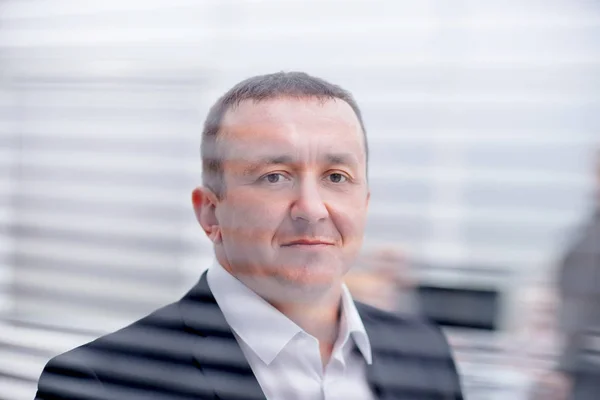 Close up. confident business man looking through office window — Stock Photo, Image