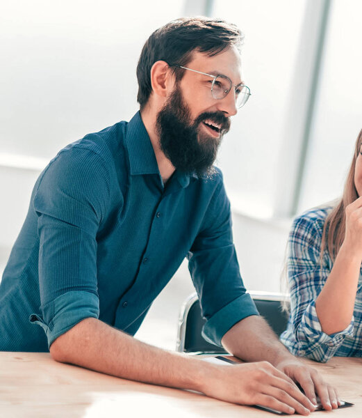 группа успешных молодых людей, сидящих за столом переговоров.