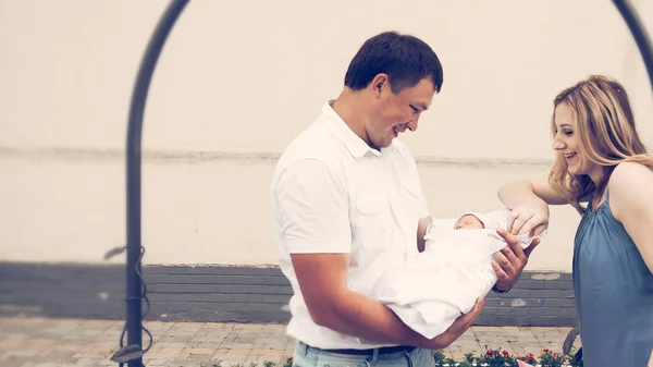 Jeunes parents avec un nouveau-né debout sous une arche près du centre périnatal — Photo