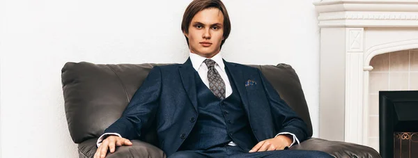 Framgångsrik ung affärsman sitter i en stol nära öppna spisen. — Stockfoto