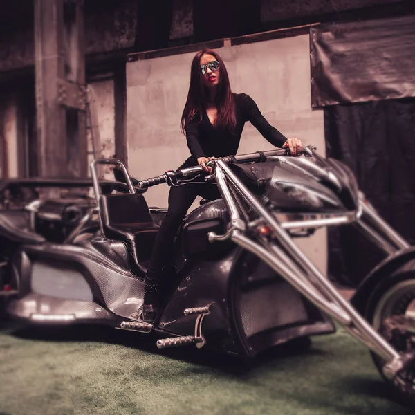 Stylisches junges Frauenmodel steht neben einem schicken Dreirad. — Stockfoto