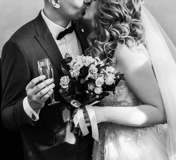På nära håll. brud och brudgum med glas champagne kysser varandra. — Stockfoto