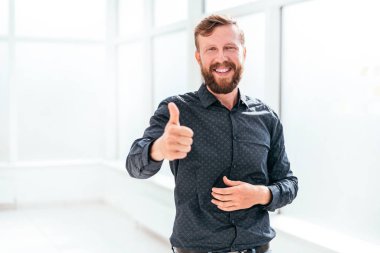 happy businessman standing in office and showing thumb up