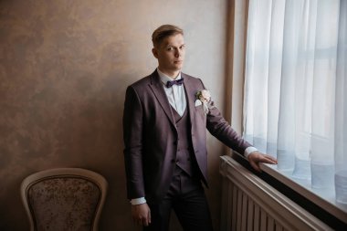 Kapat. Düşünceli damat pencerenin yanında duruyor..