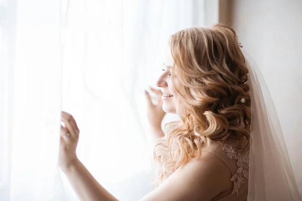 닫아. 웨딩 드레스를 입고 창가에서 있는 젊은 여자. — 스톡 사진