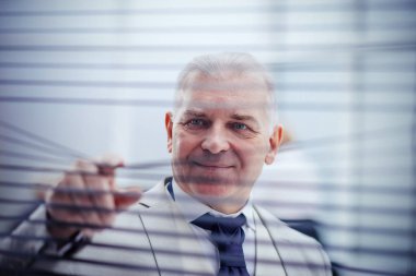 close up. smiling businessman looking through window blinds.