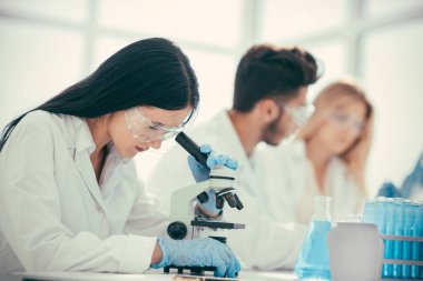 female doctor using a microscope to check for a coronavirus test