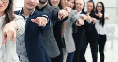 large group of young business people are pointing at you
