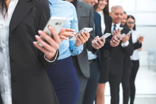Grupo de funcionários diversos com smartphones em pé em uma fileira — Fotografia de Stock