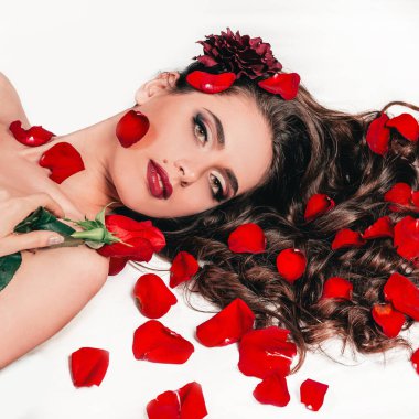 muhteşem genç kadın gül yaprakları arasında yatıyor.