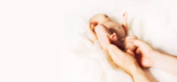 Zamazany obraz tekstu reklamowego. w plamie, z kopią miejsca. Rodzic trzymający w rękach stopy noworodka — Zdjęcie stockowe