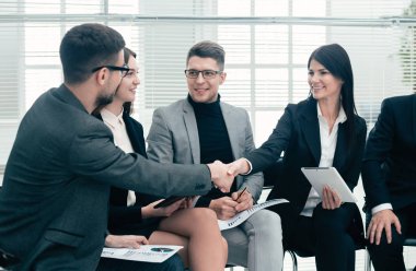 İş arkadaşları bir ofis toplantısında birbirlerini selamlıyorlar.