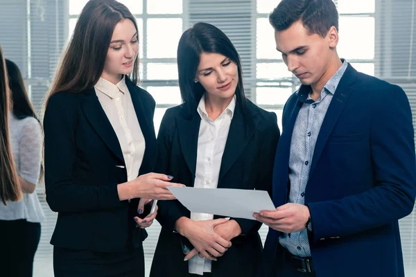 Grupo de jóvenes empleados discuten un documento de negocios . — Foto de Stock