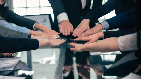 Equipo de negocios que se une a ellos en la palma de su mano sobre el escritorio . — Foto de Stock