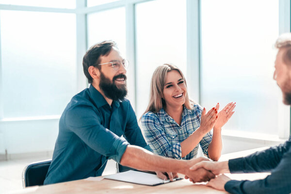 улыбающийся молодой человек отвечает на вопросы работодателей во время собеседования
