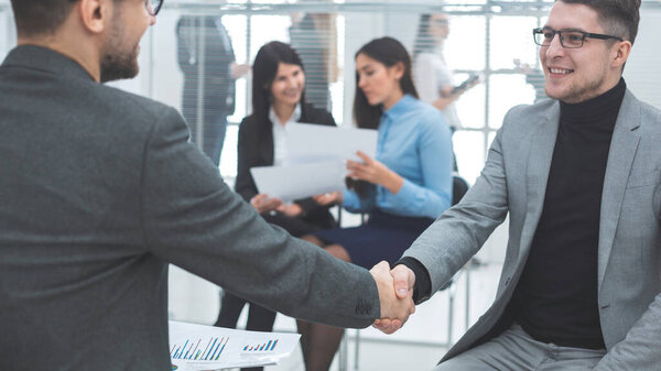 Закрывай. улыбающиеся коллеги пожимают друг другу руки