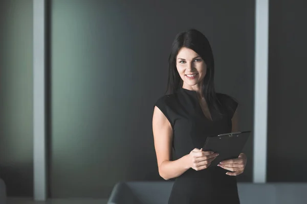 business woman with clipboard standing in office.