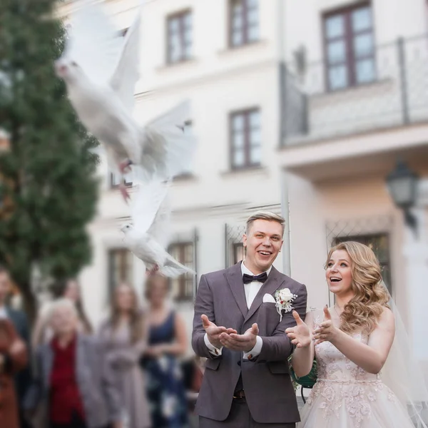 Fecha. noiva feliz e noivo liberando pombas brancas — Fotografia de Stock
