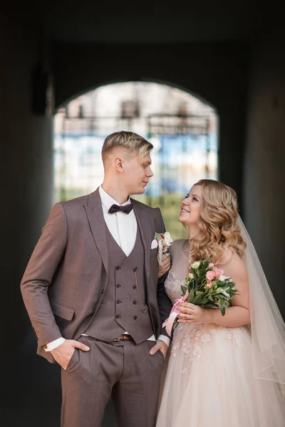 Bride and groom standing under the arch of the city building. — Stock Photo, Image