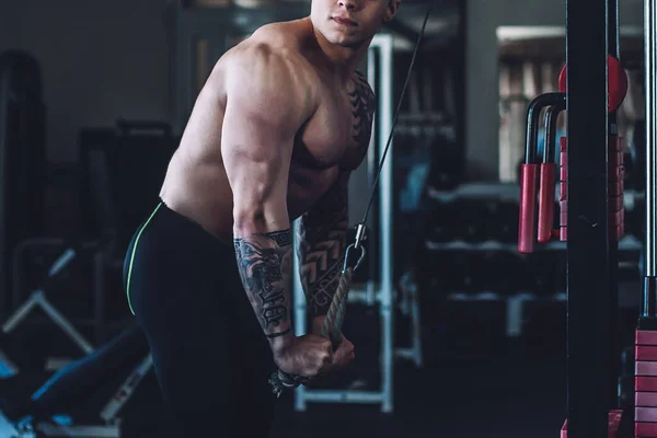 Muskularny kulturysta używa trenera do pompowania triceps — Zdjęcie stockowe