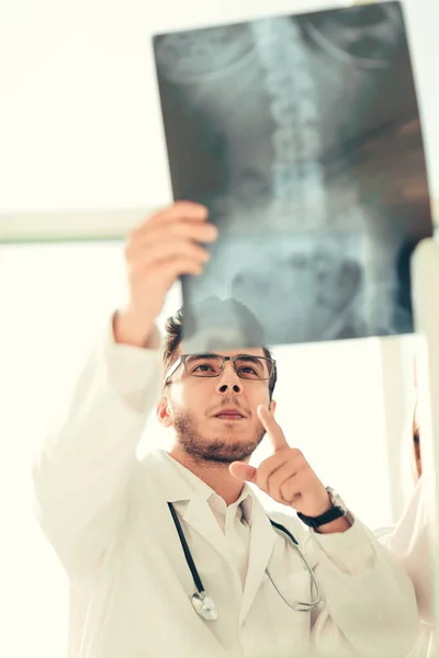 Ortopedi uzmanı doktor gülümseyen x - ray hastanın görünüyor — Stok fotoğraf