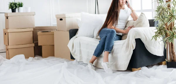 Mujer joven haciendo un pedido en su teléfono inteligente en un nuevo apartamento — Foto de Stock