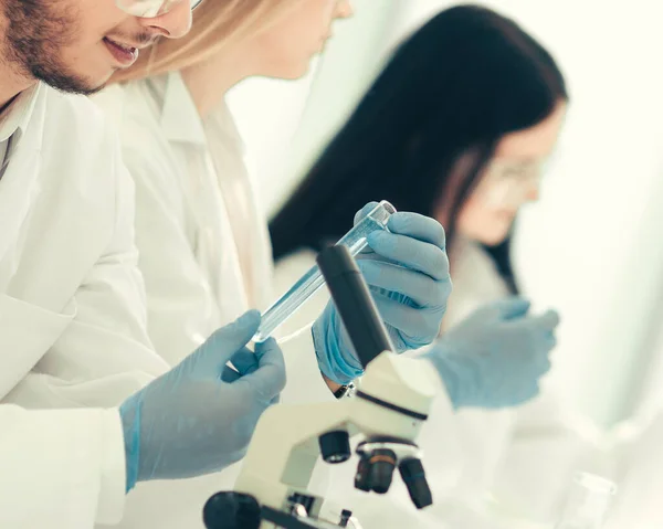 Grupo de jovens biólogos sentados à mesa do laboratório — Fotografia de Stock