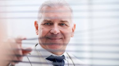 close up. smiling businessman looking through window blinds.