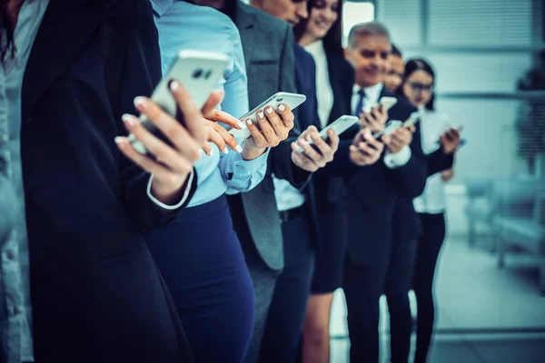 Grupo de funcionários diversos com smartphones em pé em uma fileira — Fotografia de Stock