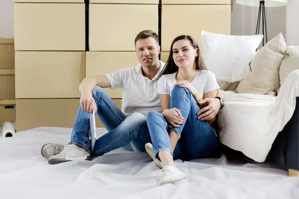 Feliz pareja sentada cerca de cajas en un nuevo apartamento — Foto de Stock