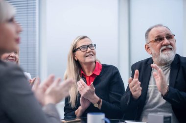 Kapat. Bir grup iş adamı iş toplantısı sırasında alkışlıyorlar..