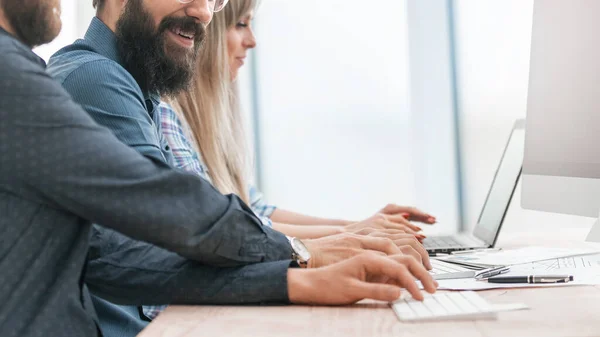 De cerca. hombre de negocios sonriente y sus colegas sentados en el escritorio — Foto de Stock